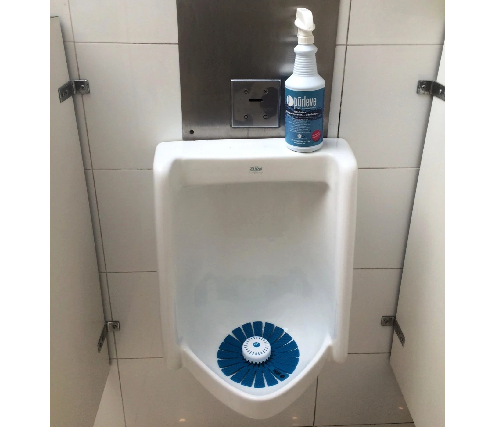 Urinario con pantalla azul y un envase de limpiador junto al sistema de descarga