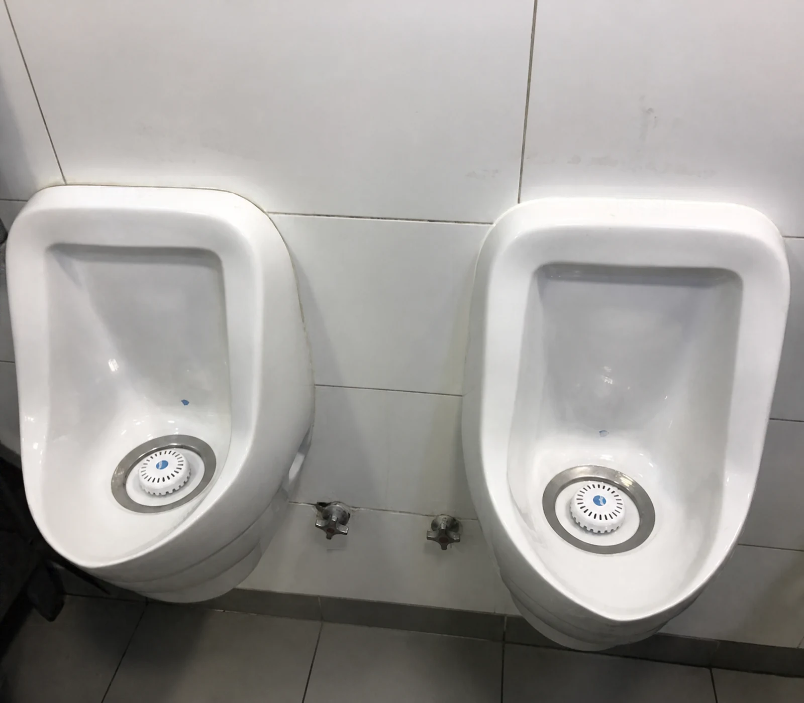 Dos urinarios instalados sobre un muro de cerámica
